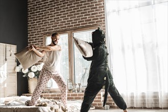 Woman costume pillow fighting with her husband home