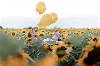 Woman holding balloons sunflower field