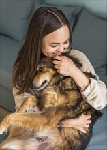 Woman petting her cute dog home during pandemic