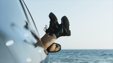 Woman s feet out car window near sea