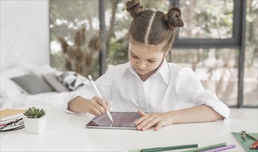 Young girl studying tablet with pen