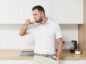 Young man tshirt sipping coffee kitchen