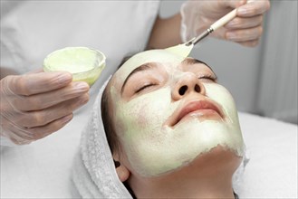 Beautician applying face mask female client 2
