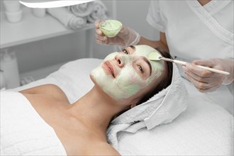 Beautician applying face mask female client 4