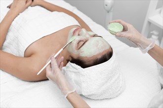 Beautician applying face mask female client 7
