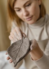 Close up blurry woman holding clay leaf