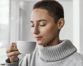Close up woman smelling coffee