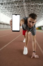 Full shot athlete holding smartphone