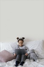 Little girl bed with headphones using tablet 3
