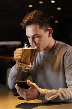 Medium shot man drinking beer pub