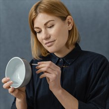 Medium shot young woman painting bowl