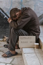 Side view homeless man stairs with cup help sign