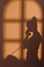 Silhouette young woman home with window shadows