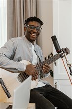 Smiley male musician home playing guitar singing