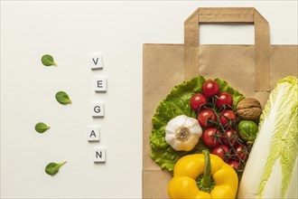 Top view assortment vegetables with word vegan paper bag