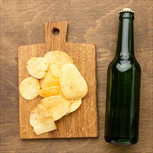 Top view beer bottle with chips cutting board