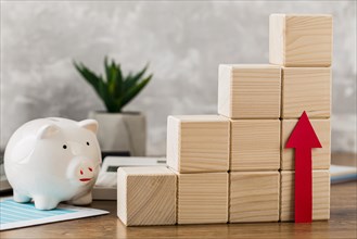 Piggy bank with wooden growth blocks arrow pointing up