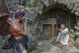 Sculpture of the devil and St Anthony of Padua at grotto in the village Crupet