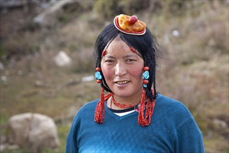 Portrait of Tibetan Khampa woman wearing traditional amber and red coral hair piece at Zhuqing