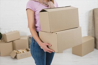 Mid section young woman holding stack cardboard boxes