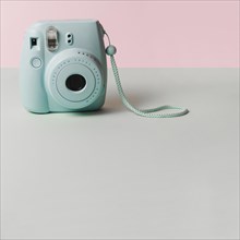 Mini blue instant camera gray desk against pink background