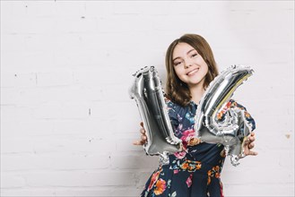 Smiling portrait girl showing numeral 14 foil balloon