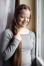 Smiley girl with down syndrome posing by window