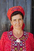 Close-up portrait of Turkmen woman wearing red headscarf and koynek
