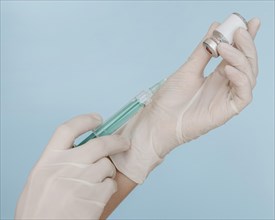 Hands with gloves holding syringe with vaccine bottle