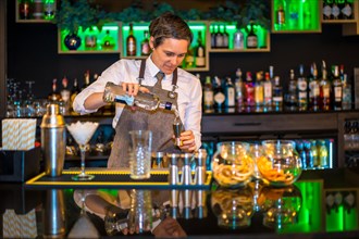 Portrait of a professional female bartender using a dispenser to prepare a luxury cocktail