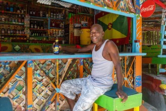 Local black man drinking Carib beer at Charlie's Bar on Happy Hill