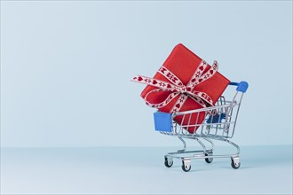 Wrapped red gift box shopping cart blue background