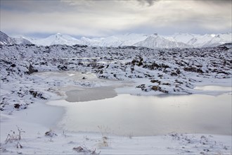 Frozen pond and snow covered mountains in winter