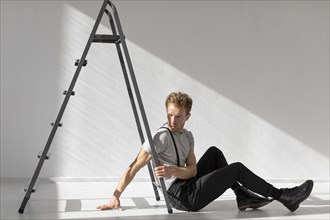 Sideways man sitting floor ladder