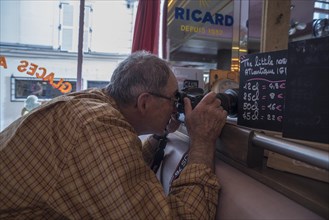 Elderly gentleman taking photos in a cafe