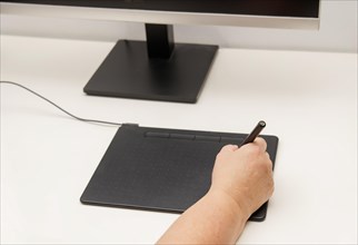Woman hand working on her computer with a digital graphic tablet
