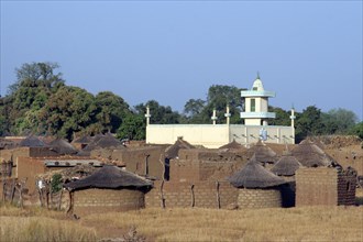 Stone huts with thatched roofs and mosque in village at Burkina Faso