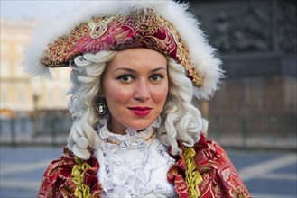 Russian woman in 18th century period dress posing for tourists by the Hermitage Winter Palace on Palace Square in the city Saint Petersburg
