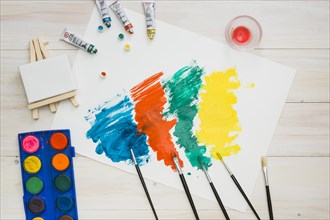 Multicolored brushstroke white page with painting equipment wooden table