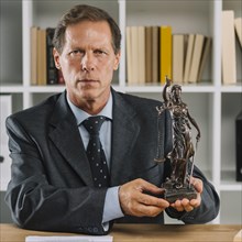 Close up confident mature male lawyer showing justice statue