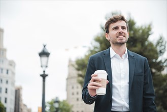 Portrait smiling young businessman holding takeaway coffee cup hand