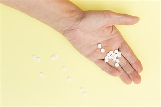 White round tablets hand person against yellow background