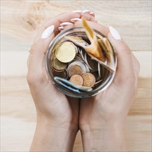 Woman s hand holding saving jar against wooden background