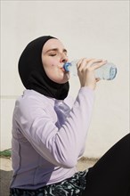Woman with purple jacket drinking water