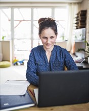Smiling woman working laptop home