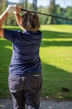 Female Golfer Making a Golf Swing in a Sunny Day in Switzerland