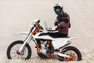 Motorbike rider with helmet holding laptop