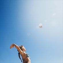 Woman playing beach volley with sun background