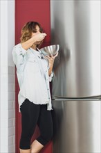Woman standing eating near fridge