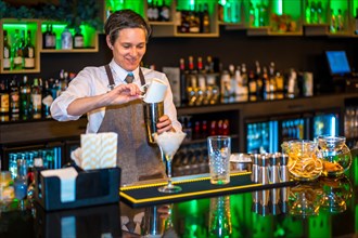 A professional bartender making luxury cocktail mixing ingredients on a shaker in the counter
